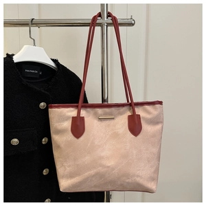 Detail of beige suede tote bag with red leather trim and golden metal bar hardware