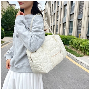 Close-up of quilted heart embroidery and zipper pocket on a beige large tote bag