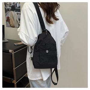 Detail of black nylon chest bag with adjustable strap and M logo on a model
