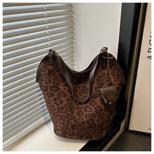 Detail of leopard print tote bag with brown leather straps and small pouch charm