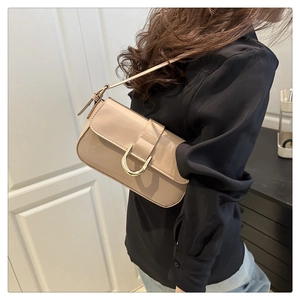 Beige lakslederen schoudertas met gouden gesp op model voor een urban stijl