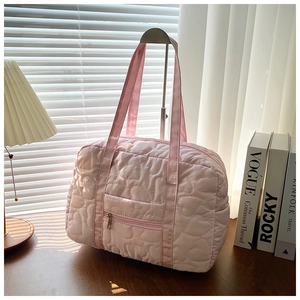 Detail of pink heart-quilted nylon travel bag with front zipper pocket on metal stand