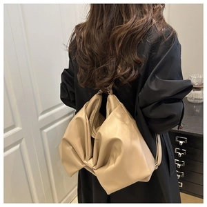 Borsa tote in morbida pelle beige con design a pieghe indossata sulla spalla del modello