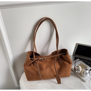 Detail of vintage caramel suede tote bag with metal buckles in a minimalist workspace