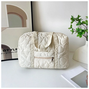 Detail view of white quilted tote bag featuring heart patterns and front zipper pocket