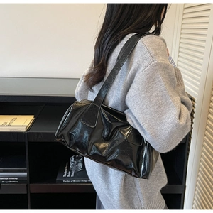 Detail of black glossy patent leather shoulder bag with vintage crinkle texture and wide strap