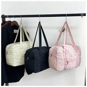 Three colors of quilted heart travel bags hanging on a rack with front zipper pockets