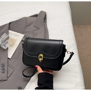 Detail of a vintage black leather crossbody bag featuring a golden circular metal clasp