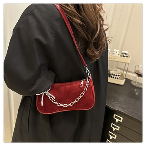 Detail view of red velvet shoulder bag with silver chain and rhinestone bow charm