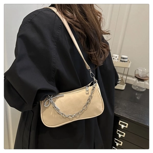 Close-up of beige half-moon shoulder bag with sleek silver chain and leather strap details