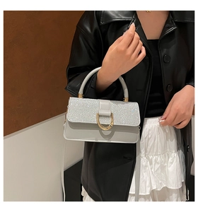 Detail of light gray glitter handbag with gold horseshoe buckle and chain strap
