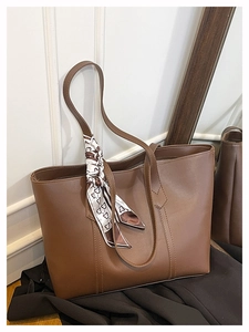 Detailed shot of a brown tote bag with a geometric print scarf on the handle