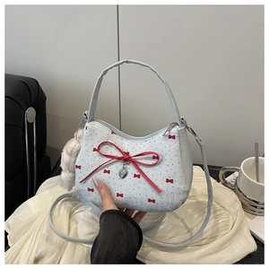 Détail du sac à main pour femme avec imprimé nœud rouge et pendentif boule peluche