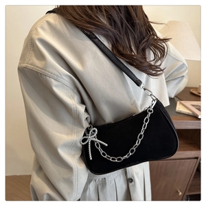 Détail du sac bandoulière en suède noir avec chaîne argentée et nœud strassé