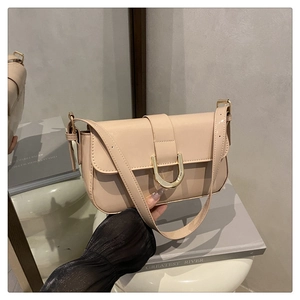 Detail shot of beige patent leather bag featuring a glossy finish and gold horseshoe buckle