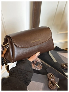 Dettaglio borsa vintage marrone con ciondolo di perline e tracolla a fantasia