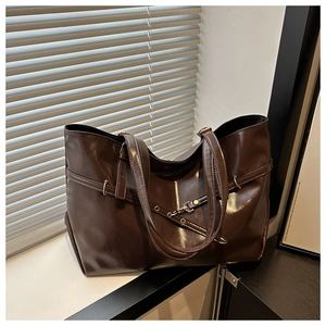Close-up of deep coffee leather tote bag featuring metallic eyelets and lobster clasp detail
