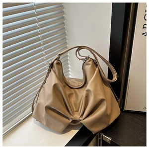 Detail of beige bow-shaped shoulder bag featuring soft pleated leather and zipper closure