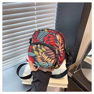 Detail of colorful leaf pattern on durable nylon crossbody bag with black zippers
