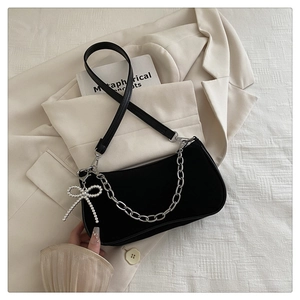 Détail d'un sac à bandoulière noir mat avec chaîne argentée et charm nœud perlé