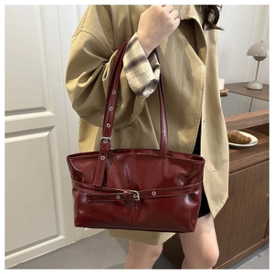 Vue latérale d'un sac à main bordeaux en cuir ciré vintage porté à l'épaule par une femme