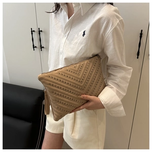 Detail of khaki V-quilted envelope bag featuring vintage bronze metal rivet studs and handle