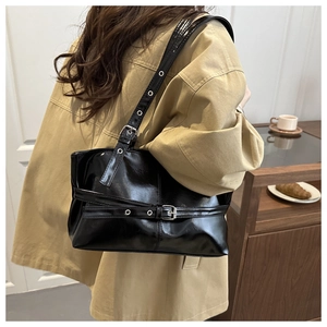 Détail d'un sac à bandoulière en cuir verni noir avec boucle argentée en scène de vie