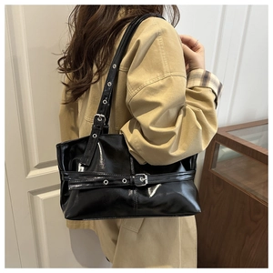 Vue détaillée du sac à bandoulière en cuir ciré noir avec œillets et boucles en métal