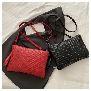 Close-up of quilted leather envelope bags with metallic rivets in red and black colors
