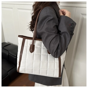 Detail view of large quilted checkered tote bag with brown contrast straps and matte finish