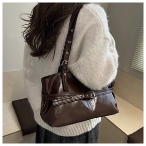Détail du sac bandoulière en cuir brillant marron foncé avec boucles et œillets