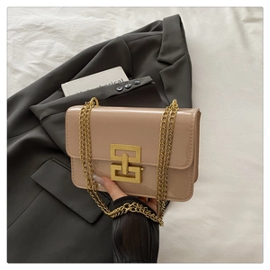 Close-up of nude beige patent leather crossbody bag with gold chain and square metal lock