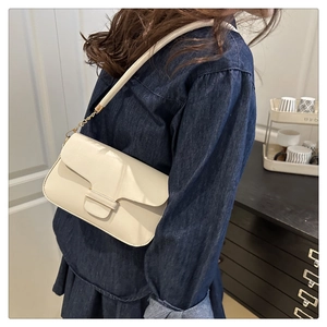 Détail d'un sac à bandoulière en cuir blanc crème avec chaîne dorée et boucle en U