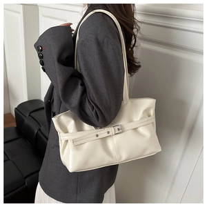 Detail view of cream leather tote bag with metallic buckle and elegant pleated edges