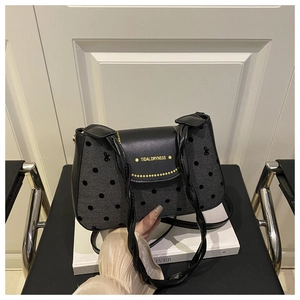 Détail de la texture grise à pois et du rabat en cuir noir avec logo de marque doré