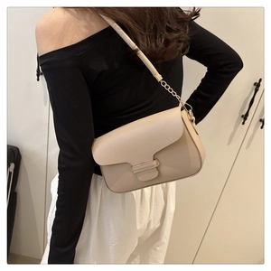 Detail of a beige minimalist shoulder bag with a gold metal clasp and chain strap