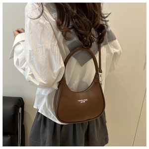 Close-up of brown leather crescent bag with fashion gold lettering and zipper detail