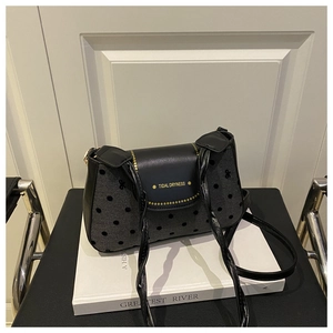 Détail du sac en toile à pois noirs avec rabat en cuir et lettrage doré élégant