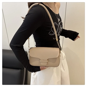Detail of beige shoulder bag featuring matte leather texture and gold chain strap