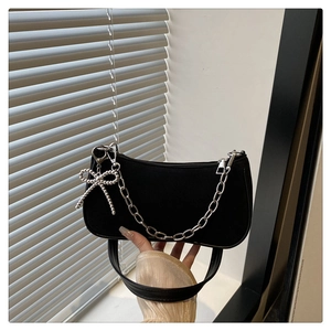 Détail du sac croissant en daim noir avec chaîne argentée et breloque nœud perlé