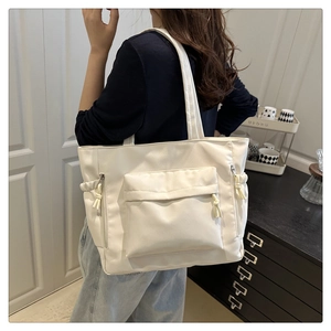 Detail of white large capacity tote bag with front zipper pocket and drawstring sides
