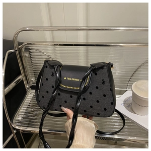Détail du sac à bandoulière chic à pois avec inscription dorée élégante sur le rabat