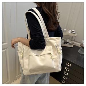 Close-up of off-white tote bag with three-dimensional zipper pocket and drawstring detail