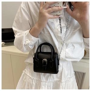 Close-up of black lychee-grain mini crossbody bag with silver buckle and thin chain strap