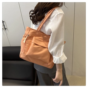 Detail view of vibrant orange tote bag showing wide shoulder strap and side zipper pocket