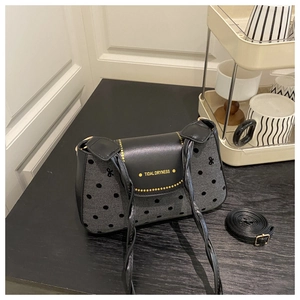 Gros plan sur la texture à pois et la poignée tressée du sac à bandoulière