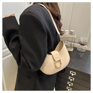 Dettaglio di una borsa a sella beige con fibbia a D dorata sulla tracolla