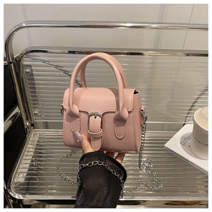 Close-up of pink leather crossbody bag featuring silver chain strap and metal buckle detail