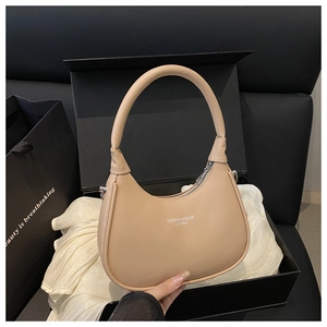Detail of beige crescent bag with silver zipper and leather texture in premium packaging