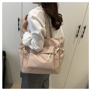 Detail of pink nylon tote bag with functional pockets and white knotted zipper pulls